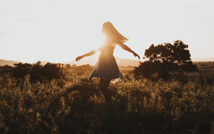 Woman twirling in a field with sunshine